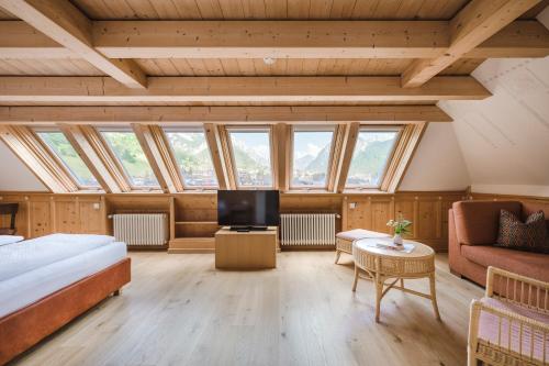 a bedroom with a bed and a tv and windows at Hotel Monte Sella in San Vigilio Di Marebbe