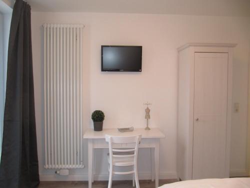 radiador blanco en una habitación con mesa y TV en Pension Willebuhr, en Mayen