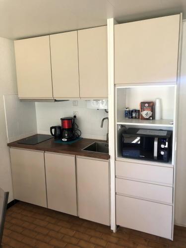une petite cuisine avec des armoires blanches et un micro-ondes dans l'établissement Appartement Cap D'Agde, au Cap d'Agde