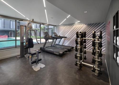 a fitness room with a gym with a swimming pool at Oakwood Studios Sukhumvit Bangkok in Bangkok