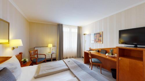 a hotel room with a bed and a flat screen tv at Schlosshotel Kassel in Kassel