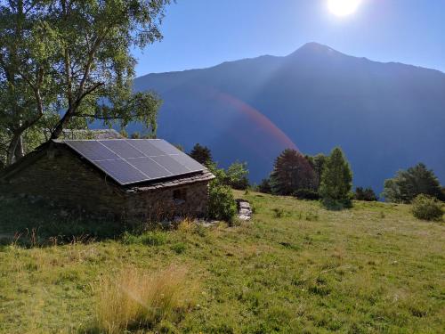 a house with a solar panel on the roof with a rainbow in the background at Bordes Pirineu, Costuix in Areu