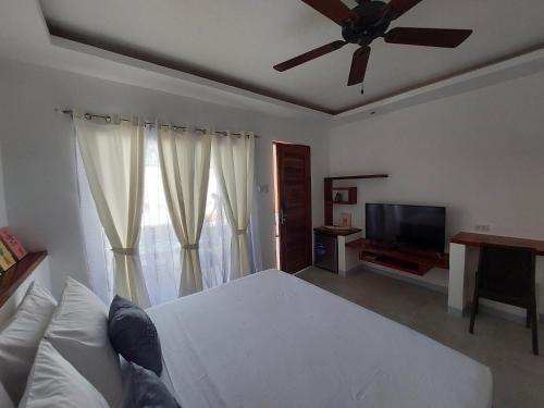 Schlafzimmer mit einem weißen Bett und einem Deckenventilator in der Unterkunft Yellow Mango Resort Bohol in Panglao