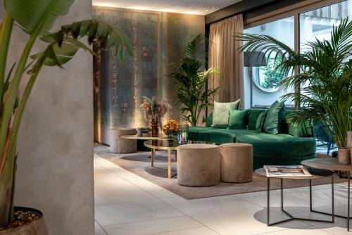 a living room with a green couch and tables at We Me Suite Hotel in Riccione