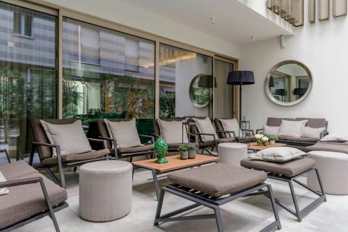 a patio with chairs and tables and a mirror at We Me Suite Hotel in Riccione