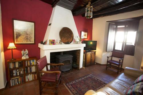 a living room with a fireplace and red walls at Casa Estrella in Alájar