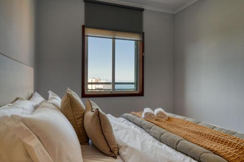 een slaapkamer met een bed met kussens en een raam bij Forum Escape, a Home in Madeira in Funchal