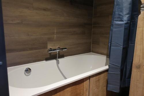 a bath tub with a water faucet on it at L'Atelier - Gîte urbain chaleureux in Saint-Hubert