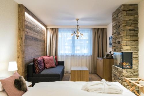 une chambre d'hôtel avec un lit, une chaise et une cheminée dans l'établissement Pfefferkorn's Hotel, à Lech am Arlberg