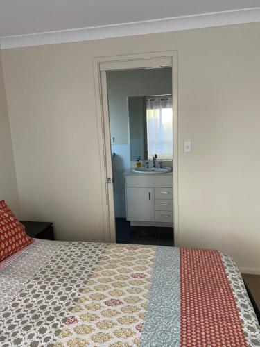 1 dormitorio con 1 cama y baño con lavamanos en Private room with ensuite and parking close to Wollongong CBD, en Wollongong