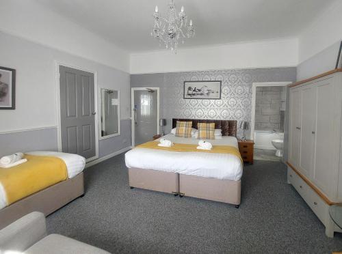 1 dormitorio con 2 camas y lámpara de araña en The Black Lion Royal Hotel, en Lampeter
