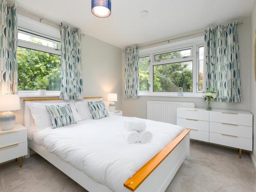 a bedroom with a large bed and two windows at The Pines in St Ives