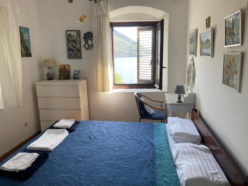 a bedroom with a blue bed and a window at Be happy in Perast in Perast