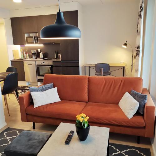 ein Wohnzimmer mit einem orangenen Sofa und einer Küche in der Unterkunft Ihana uusi huoneisto, hyvällä sijainnilla in Seinäjoki