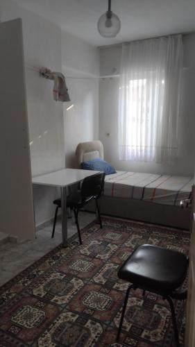 een kleine kamer met een bed, een tafel en een stoel bij Kuskayasi Apart 