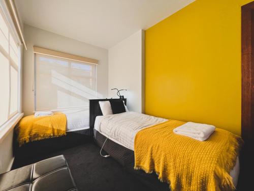 Cette chambre jaune comprend un lit et une chaise. dans l'établissement Rose Court Apartments "Aristone", à New Town