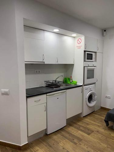cocina con armarios blancos y lavadora en Portalegre, en Madrid