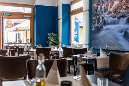 un restaurant avec des tables et des chaises et un grand tableau sur le mur dans l'établissement Hotel Lory - Molveno - Dolomiti, à Molveno