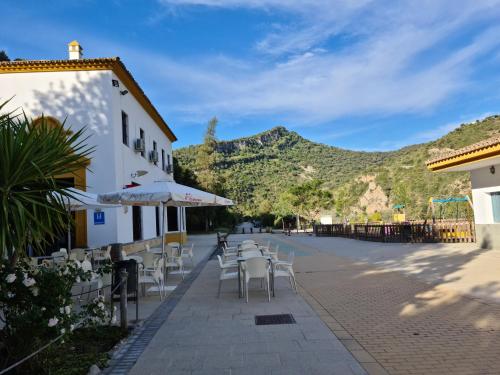 Un patio con mesas y sillas con montañas al fondo. en Estación de Coripe, en Coripe