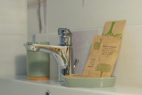 un lavandino con rubinetto e una tazza con una pianta di Maga Mirò - Guest House a Salerno
