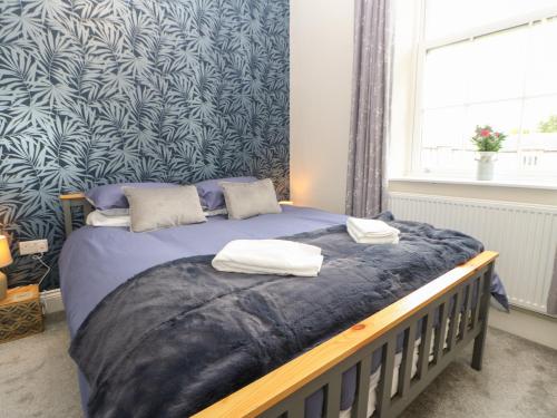 a bedroom with a bed with a blue patterned wall at 1 Claire House Way in Barnard Castle