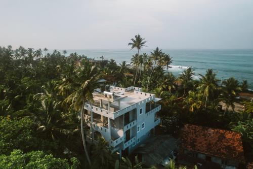 an aerial view of a house with palm trees and the ocean at Plantation Surf Inn & Restaurant - Midigama in Midigama