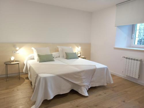 ein großes weißes Bett mit weißer Bettwäsche und grünen Kissen in der Unterkunft Apartamentos Pico de Langre in Langre