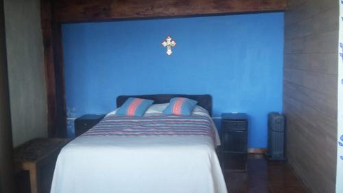 a blue bedroom with a bed with a cross on the wall at Cabaña Aurora in Zirahuén