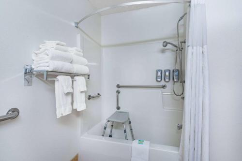 a white bathroom with a shower and a stool in it at Baymont by Wyndham Bozeman in Bozeman