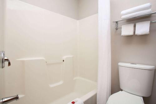 a white bathroom with a toilet and a bath tub at Days Inn by Wyndham Kansas City International Airport in Kansas City