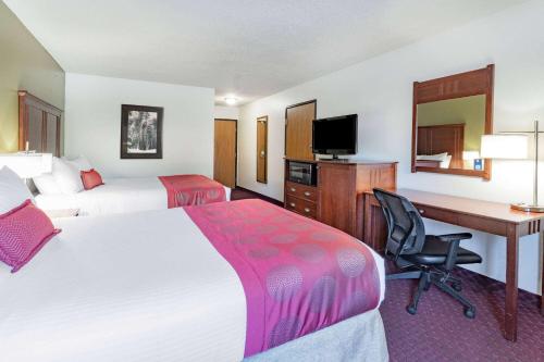 a hotel room with two beds and a desk at Baymont by Wyndham Bozeman in Bozeman