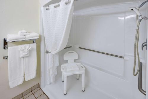 a white bathroom with a shower and a stool at Microtel Inn & Suites by Wyndham Plattsburgh in Plattsburgh
