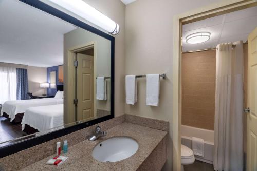 Days Inn by Wyndham Clarksville North EXIT 4 في كلاركسفيل: حمام مع حوض ومرآة كبيرة