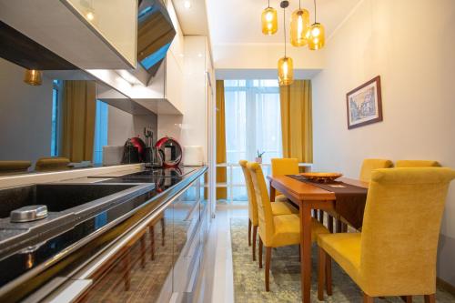cocina y comedor con mesa de madera y sillas amarillas en Dani City Center Apartment, en Belgrado