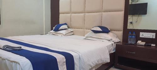 a bed with blue and white sheets and a mirror at Hotel Presidency Inn in Kolkata