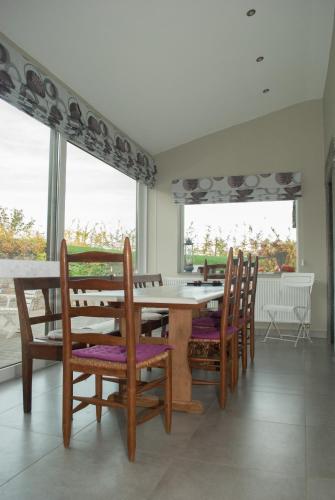 a dining room with a table and chairs and windows at Chez Peponne in Dinant