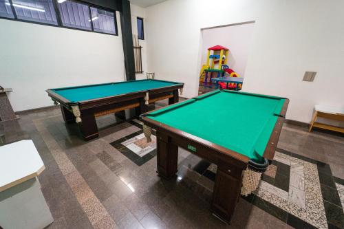 two pool tables in a room with a play area at Condall Palace Hotel in Nova Prata