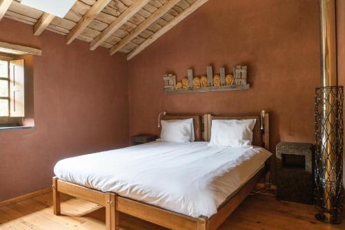 a bedroom with a large bed with white sheets at Cerdeira - Home for Creativity in Lousã
