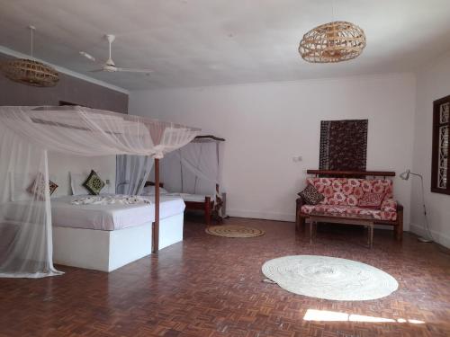 a bedroom with a bed with a canopy and a chair at Culture's apartment in Paje