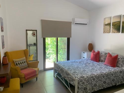 a bedroom with a bed and a chair and a window at Bay Cottage Beautiful cosy luxury cottage - Beach area in Pissouri