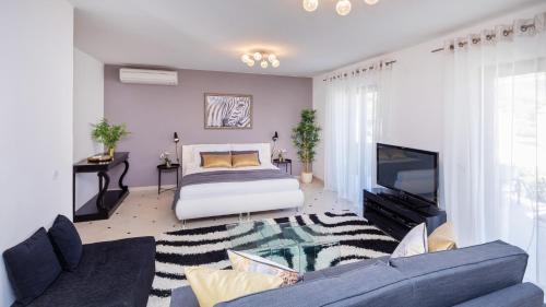 1 dormitorio con 1 cama, TV y sofá en Palm Apartments with Swimming pool, en Mlini