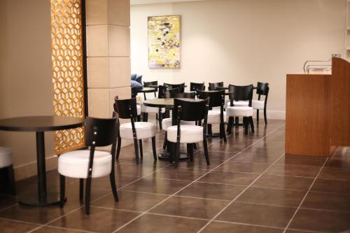 a dining room with black tables and white chairs at Rahhal Hotel Suites in Yanbu