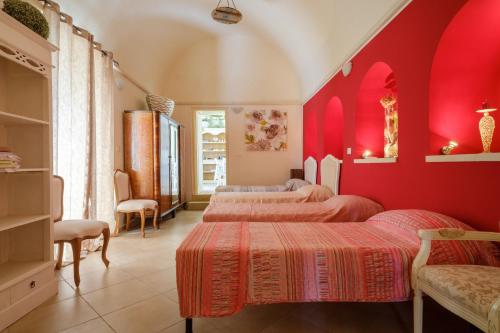 1 Schlafzimmer mit 3 Betten und roten Wänden in der Unterkunft Appartamento 2 - Palazzo Costantini in San Donato di Lecce