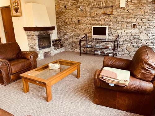 a living room with leather furniture and a stone wall at VillaPark Garden House in Szerencs