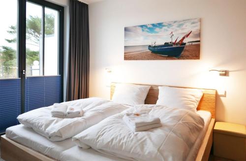 a bedroom with a white bed with a boat on it at Baabe Villa Andrea Ferienwohnung P in Baabe