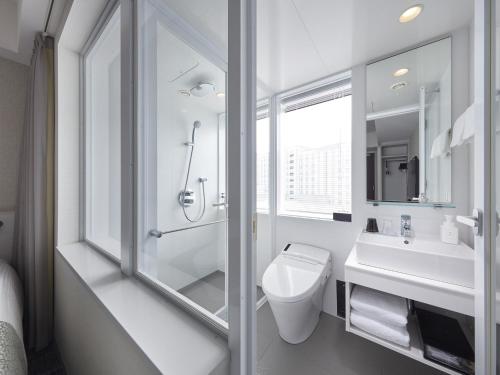 a bathroom with a shower and a toilet and a sink at Villa Fontaine Grand Haneda Airport in Tokyo