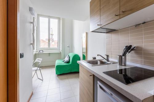 uma cozinha com um lavatório e um sofá verde em Central Studio APTS Milano-Corso Magenta em Milão