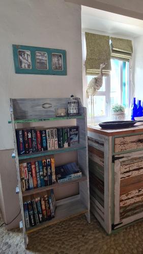 a book shelf filled with books next to a desk at Casa Pescador Beach House in Struisbaai