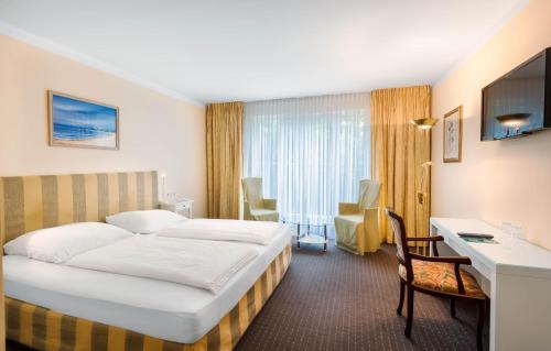 a hotel room with a bed and a desk at ALPHA HOTEL Hermann von Salza in Bad Langensalza