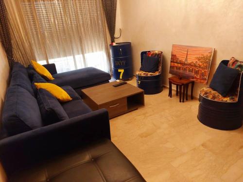 ein Wohnzimmer mit einem blauen Sofa und 2 Stühlen in der Unterkunft Bouskoura, Joli appartement coup de cœur in Bouskoura